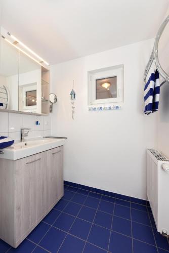 a bathroom with a sink and a blue tile floor at Ferienhaus Nordseeschnecke in Bensersiel