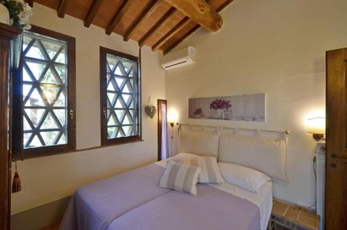 a bedroom with a bed with white sheets and two windows at La Capannina in Le Grazie