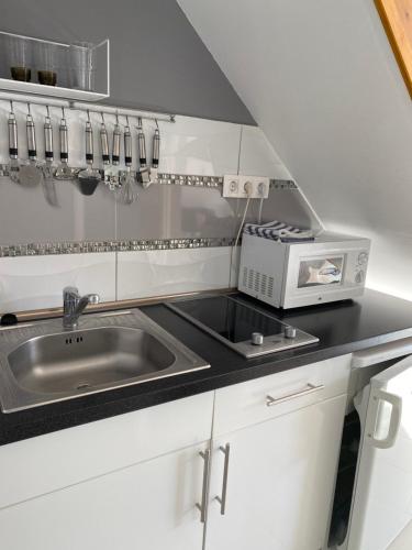 a kitchen with a sink and a microwave at Rita Apartmanház in Bük