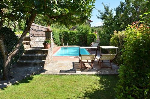 a swimming pool in a yard with two chairs and a table at Ciacchieri in Gaiole in Chianti