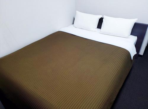 a bed with two pillows on top of it at Hotel Trend Mikawaanjo in Anjomachi