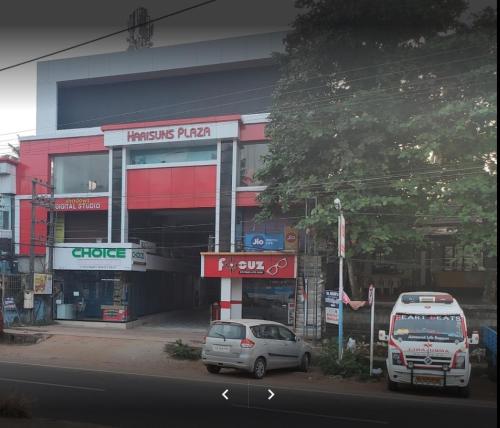 two cars parked in front of a building at Harisuns Plaza in Attingal