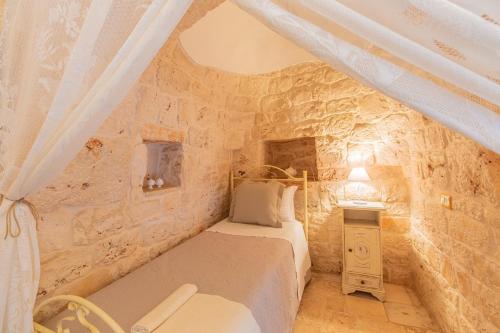 Un dormitorio con una cama en una pared de piedra. en Trullo con piscina baby, en San Michele Salentino