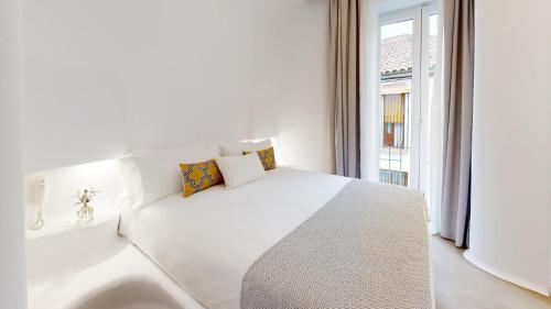 a white bedroom with a large white bed and a window at Hotel Boutique Suite Generis, Premiado El hotel más acogedor de España in Córdoba