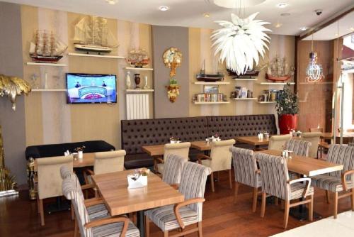 イスタンブールにあるガラタ パレス ホテルの木製のテーブルと椅子、テレビが備わるレストラン