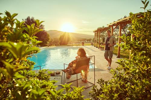 a man and a woman sitting in a chair by a pool at Agriturismo Lunadoro in Monticchiello