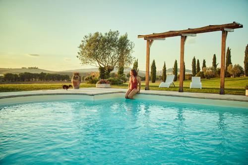 a woman is sitting next to a swimming pool at Agriturismo Lunadoro in Monticchiello