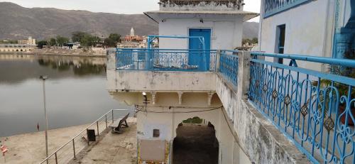 a building with a blue railing next to a body of water at Hotel Bharatpur Palace in Pushkar