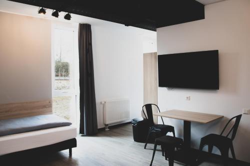 a room with a bed and a table and a tv at Das Schlafwerk Stuttgart-Nord VOLLDIGITALES HOTEL-SELF-CHECK IN - keine Rezeption-LowBudget-cashless in Korntal-Münchingen
