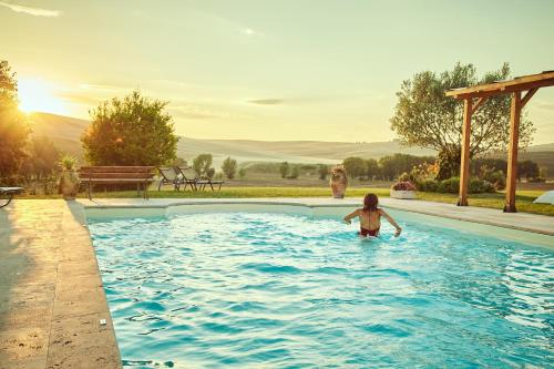a little girl standing in the water in a swimming pool at Agriturismo Lunadoro in Monticchiello