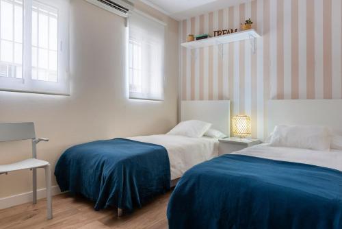 a bedroom with two beds and two windows at AlohaMundi San Luis in Seville