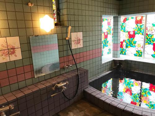 a bathroom with a tub with stained glass windows at ペンション百万本のバラ "A Million Roses" in Shimoda