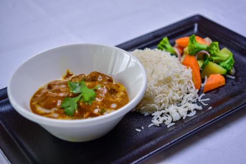 a plate of food with a bowl of soup and rice at Nairobi Safari Club by Swiss-Belhotel in Nairobi
