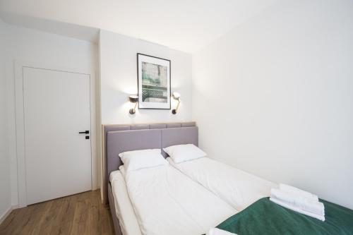 a white bedroom with a bed and a door at Marina Apartments ZOO in Wrocław