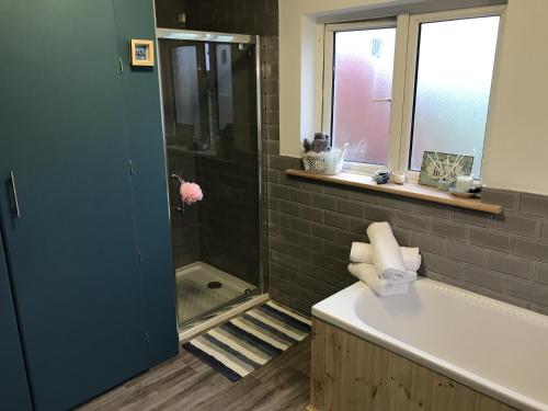 a bathroom with a shower and a tub and a sink at Rowan House Holiday Home by Trident Holiday Homes in Curranes