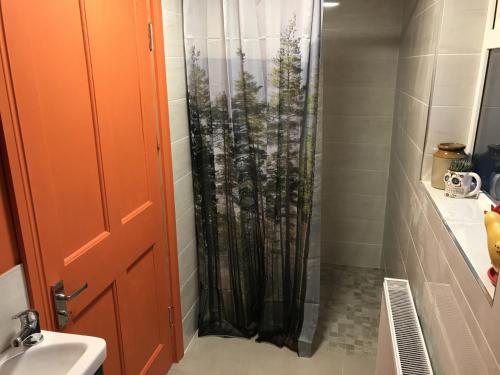 a bathroom with a shower curtain with trees at Rowan House Holiday Home by Trident Holiday Homes in Curranes