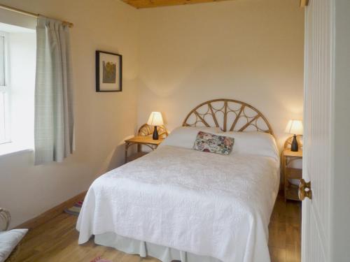 1 dormitorio con 1 cama blanca y 2 lámparas en Cappacurry Lodge Ballinrobe, en Ballinrobe