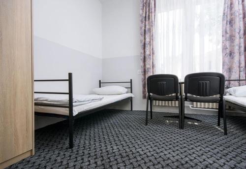 a room with two beds and two chairs at Noclegi PODZAMCZE PTTK in Przemyśl