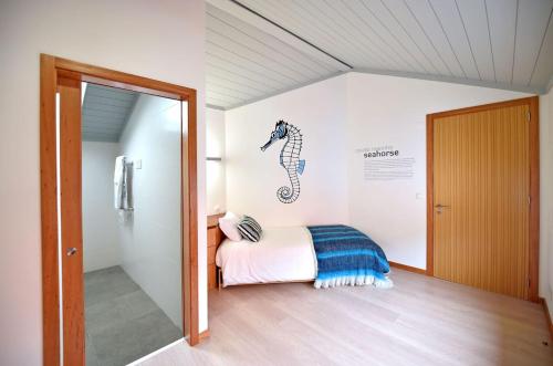 a bedroom with a bed with a seahorse picture on the wall at Casa da Baía - Guest House in Horta