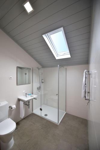 a bathroom with a shower and a toilet and a skylight at Casa da Baía - Guest House in Horta