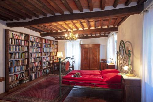 a room with a red bed in a room with bookshelves at Casa Tognarello in Borgo a Mozzano