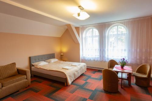 Un dormitorio con una cama, una silla y una mesa. en Sunvita, en Lądek-Zdrój