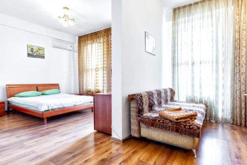 a bedroom with a bed and a couch and a chair at 423 Апартаменты в центре Отлично подходят для командированных и туристов in Almaty