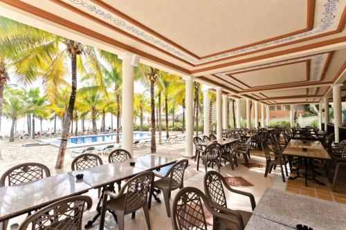 a restaurant with tables and chairs and palm trees at Riu Lupita - All Inclusive in Playa del Carmen