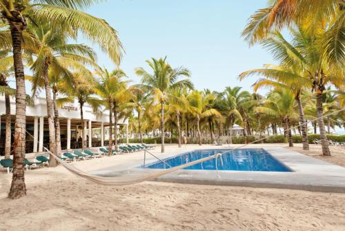 a hammock on the beach in front of a resort at Riu Lupita - All Inclusive in Playa del Carmen