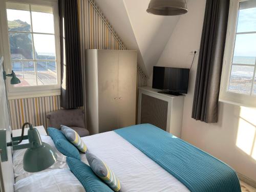 a bedroom with a bed with blue pillows on it at Les Fregates in Veulettes-sur-Mer