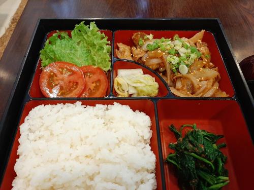 a lunch box with rice and vegetables on a table at Phạm Vân Sakura Hotel in Thuan An