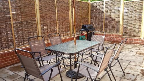 a table and chairs on a patio with a grill at Old School Apartment 2 Ground Floor in Bury Saint Edmunds