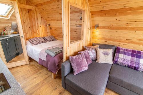 a room with a bed and a couch in a cabin at Farragon Luxury Glamping Pod with Hot Tub & Pet Friendly at Pitilie Pods in Aberfeldy