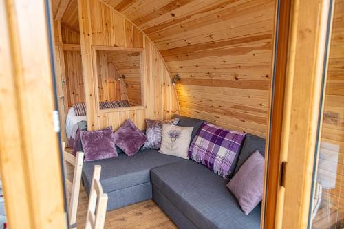 a room with a couch in a wooden cabin at Farragon Luxury Glamping Pod with Hot Tub & Pet Friendly at Pitilie Pods in Aberfeldy