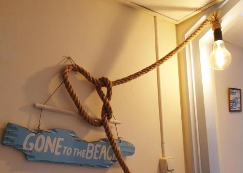 een touw hangend aan een muur met een bord en een licht bij Zeelui in Egmond aan Zee