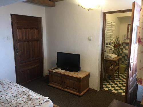 a room with a television on a wooden table and a bedroom at Pensjonat Stary Spichlerz in Ełk