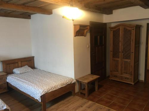 エウクにあるPensjonat Stary Spichlerzのベッドルーム1室(ベッド1台付)、木製キャビネットが備わります。