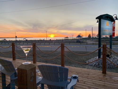 a wooden deck with chairs and a drink on the beach at Paradise Inn On the Beach in Port Elgin