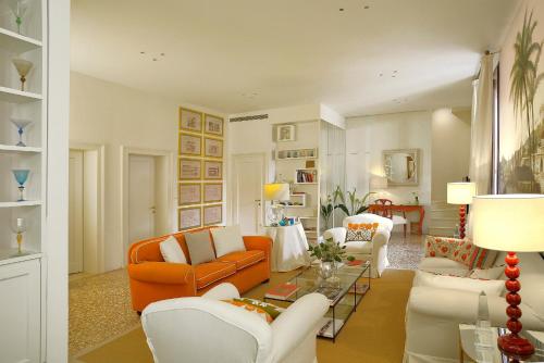 a living room with an orange couch and white chairs at Palazzo Ca'nova on the Grand Canal - Canella Apartment in Venice