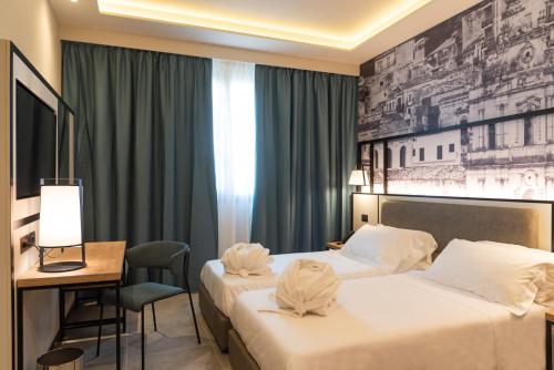 a hotel room with two beds and a desk at Modica Boutique Hotel in Modica