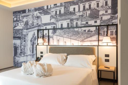 a bedroom with a large white bed with a wall mural at Modica Boutique Hotel in Modica
