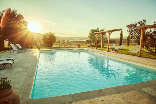 a swimming pool with the sun setting in the background at Agriturismo Lunadoro in Monticchiello