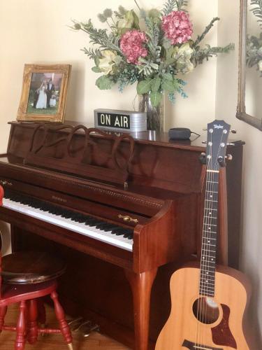 a piano and a guitar in a room with a vase of flowers at The Homestead in Madison
