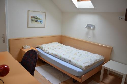 Bett in einem Zimmer mit einem Tisch und einem Stuhl in der Unterkunft Hotel Hessengüetli in Winterthur