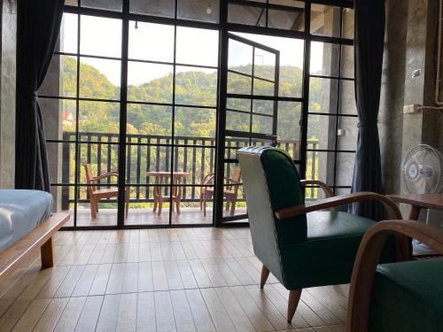 a room with a view of a balcony with a bed and chairs at PilokMyhome ที่พักเหมืองปิล็อก บ้านอีต่อง in Ban Pilok Khi