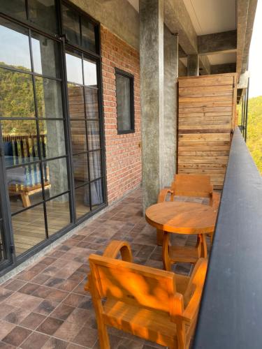 a patio with a wooden table and chairs and windows at PilokMyhome ที่พักเหมืองปิล็อก บ้านอีต่อง in Ban Pilok Khi