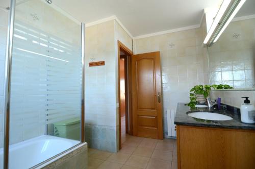 La salle de bains est pourvue d'une baignoire, d'un lavabo et d'une douche. dans l'établissement Villa La Romaguera, à Garrigolas