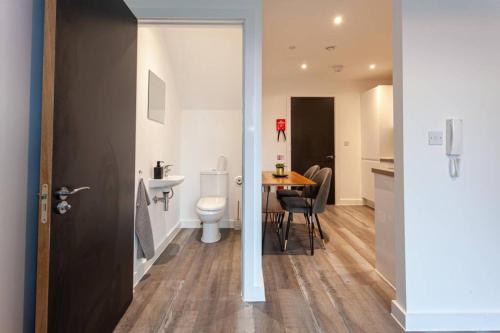 a bathroom with a toilet and a sink and a table at Superb 2 Bed Flat 5min to Old Trafford Stadium in Manchester