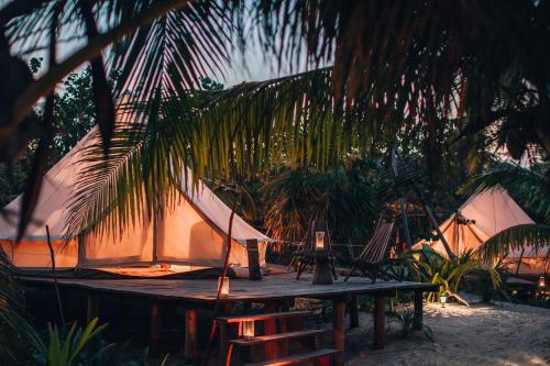 a tent on the beach with a table and some palm trees at Glamp Ikal Tulum in Tulum