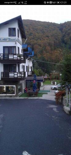 a large white house with a woman sitting on a bench at HOTEL ALL TIMES in Timisul de Jos
